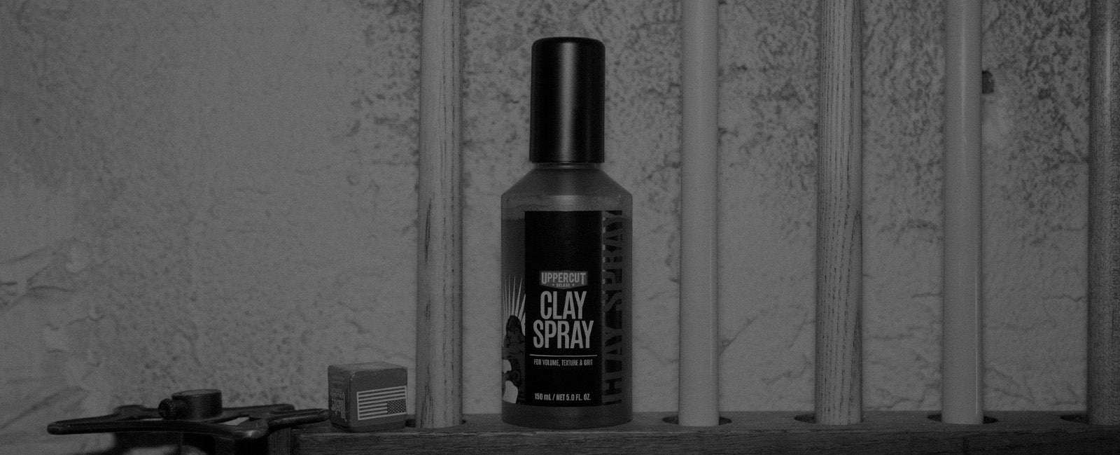 Uppercut Deluxe Clay Spray sitting next to pool cues on shelf